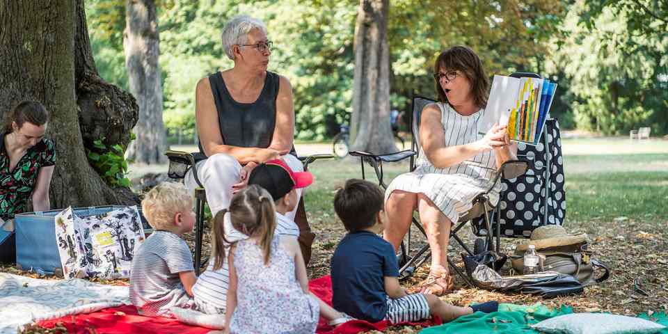 Voorlezers van leeslekker lezen voor aan kinderen in het park.
